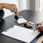 person signing a lease and being handed keys