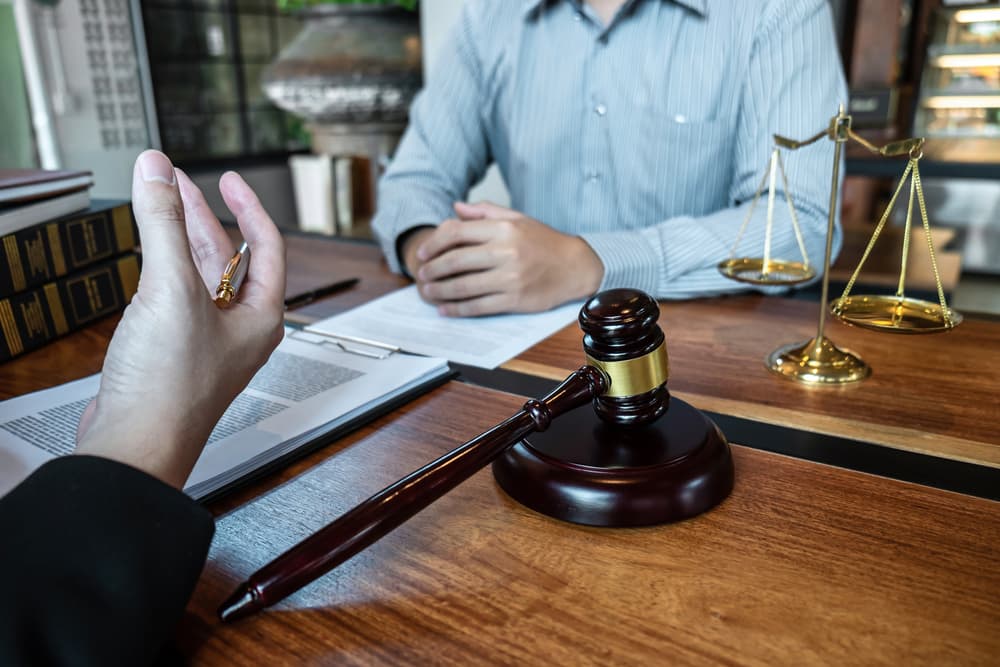 Male attorney in office discussing legal case with client, reviewing documents—a scene of law and justice, representing the attorney-client relationship.