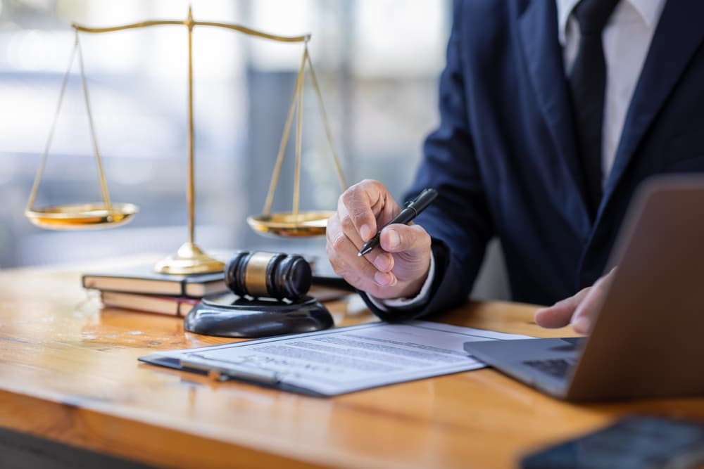 Close-up of a male lawyer, notary working in a courtroom, sitting at a wooden table in his office. Legal law, advice, deal, justice, and law concept.