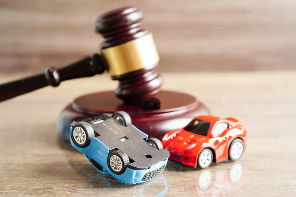 Legal concept of car accident compensation and insurance claim, with a judge's gavel next to a model car.