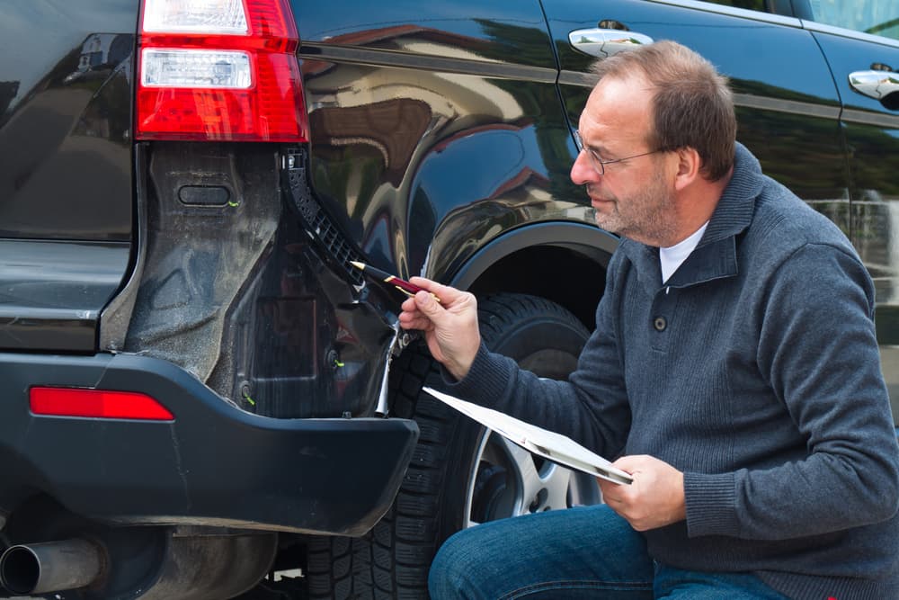 An insurance expert examines a damaged car as part of a car insurance claim process.