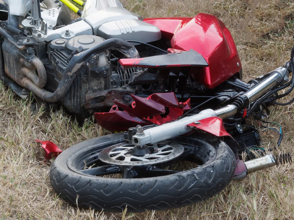 Damaged motorcycle lying on grass after an accident.