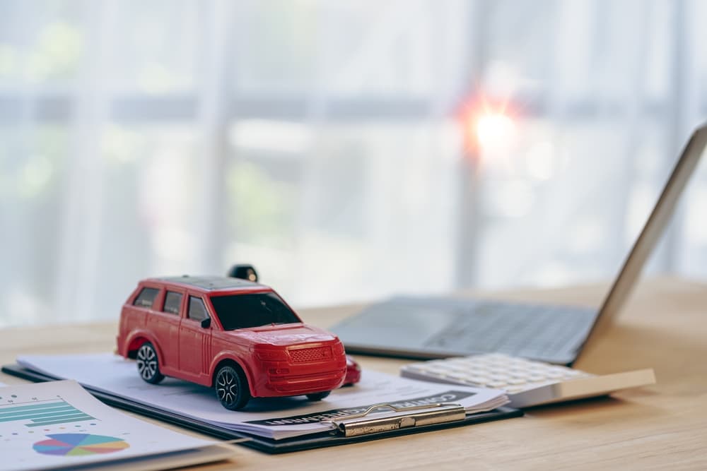 Toy car and laptop calculator on desk. Buy, sell, rent, repair or insurance, small business, car sales concept.