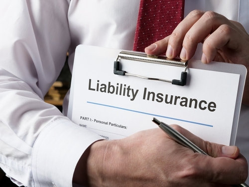 Person holding a clipboard labeled "Liability Insurance" and a pen.