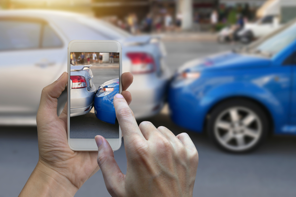 Person taking a photo of a rear end car accident with smartphone