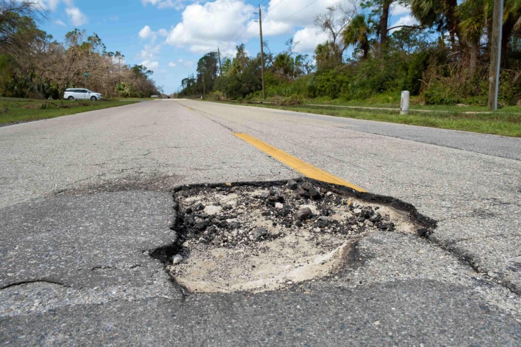 Un bache grande en medio de una carretera que crea un peligro para manejar y un posible riesgo de accidente. Un bache grande en medio de una carretera que crea un peligro para manejar y un posible riesgo de accidente.