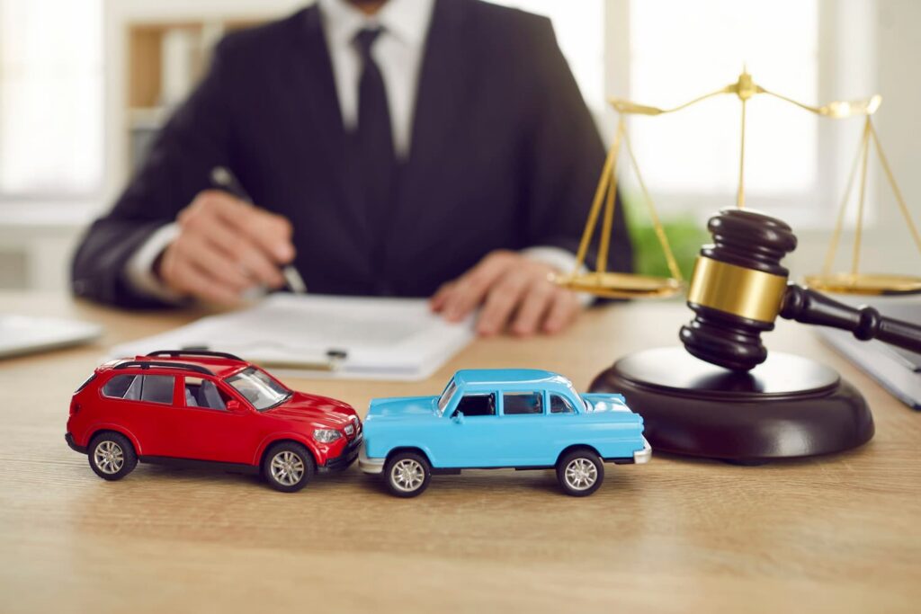 Holtsville car accident lawyer reviewing auto collision case with model cars, gavel, and scales of justice