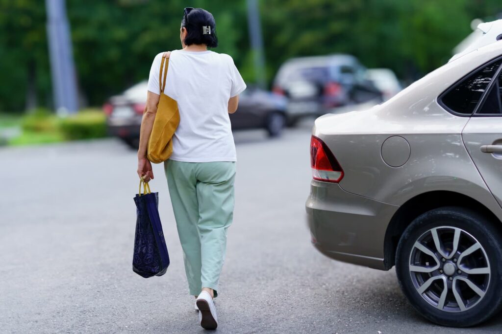 Pedestrian walking in a parking lot near a reversing car illustrating hit-and-run risk and driver negligence in shared spaces
